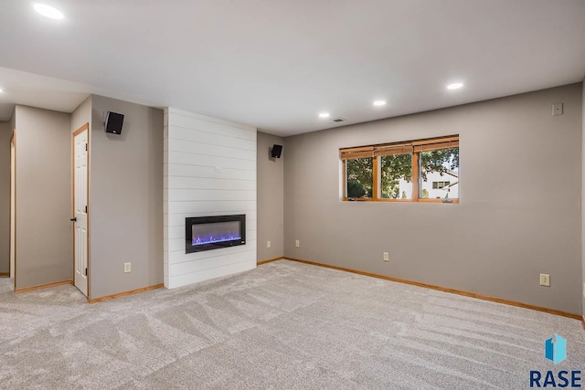 unfurnished living room featuring a large fireplace, carpet, baseboards, and recessed lighting