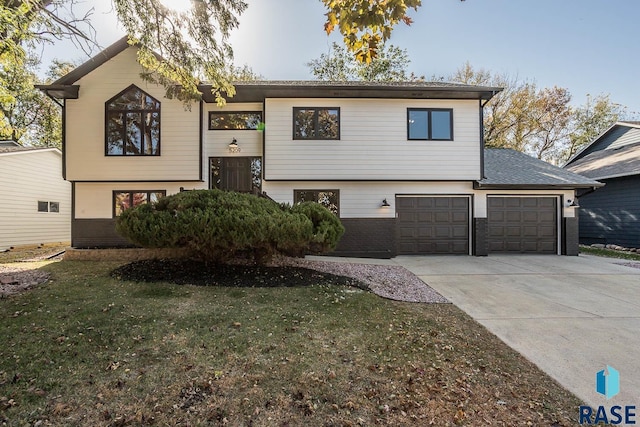 split foyer home with driveway, brick siding, and a front lawn