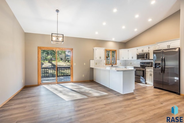 kitchen with a peninsula, a sink, white cabinets, appliances with stainless steel finishes, and decorative backsplash