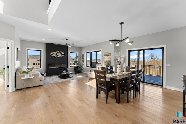 dining space with light wood-style floors, recessed lighting, a fireplace, and baseboards