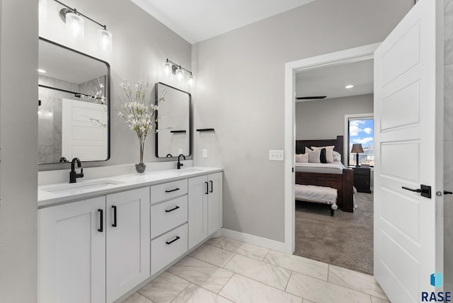 bathroom with marble finish floor, double vanity, a sink, and ensuite bathroom