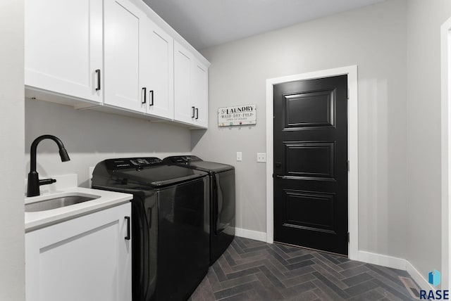 laundry room featuring brick floor, a sink, baseboards, cabinet space, and washer and clothes dryer