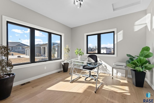 office space with wood-type flooring, visible vents, and baseboards