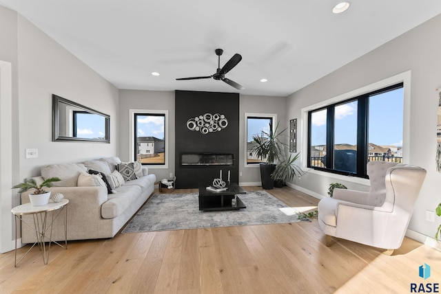 living room with a large fireplace, wood-type flooring, baseboards, and plenty of natural light