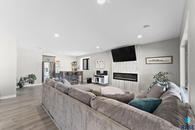 living area featuring a fireplace, light wood finished floors, recessed lighting, visible vents, and baseboards