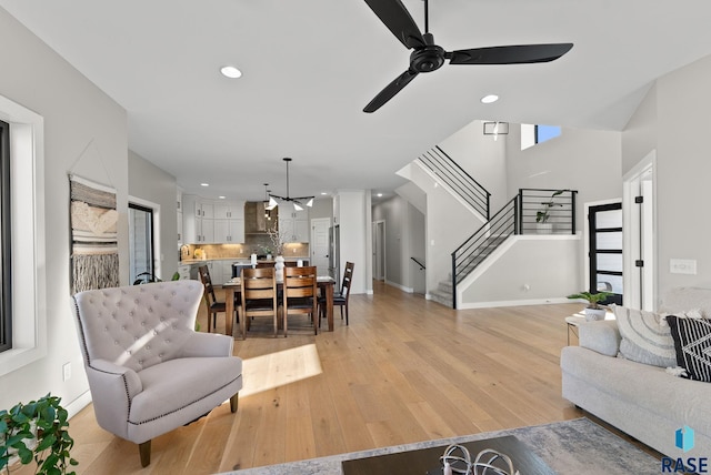 living room featuring light wood-style floors, ceiling fan, stairs, and recessed lighting