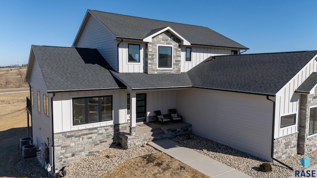 modern inspired farmhouse featuring stone siding, a shingled roof, and board and batten siding