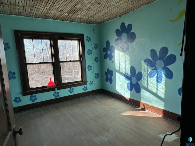 empty room featuring wood ceiling, baseboards, and wood finished floors