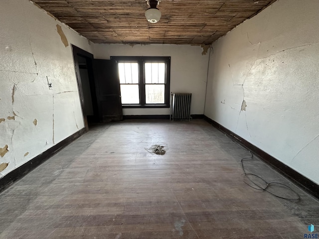 unfurnished room featuring wooden ceiling, radiator heating unit, baseboards, and wood finished floors