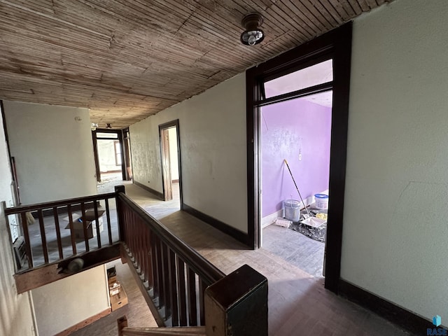 hallway with wood ceiling, baseboards, an upstairs landing, and wood finished floors