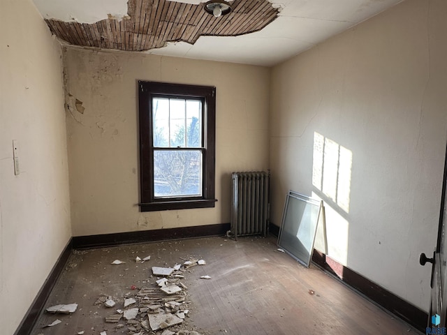 unfurnished room featuring radiator and baseboards