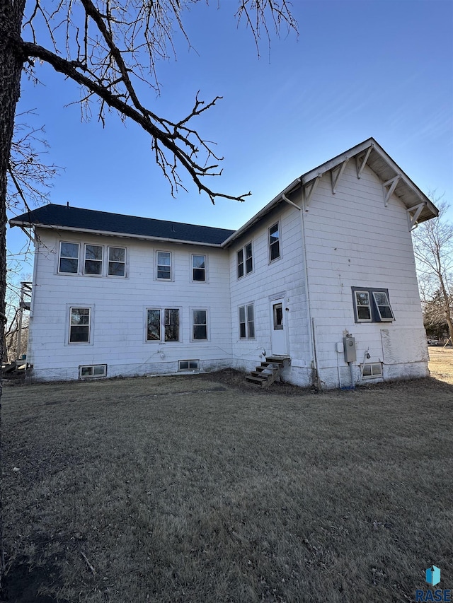 rear view of property with entry steps and a lawn