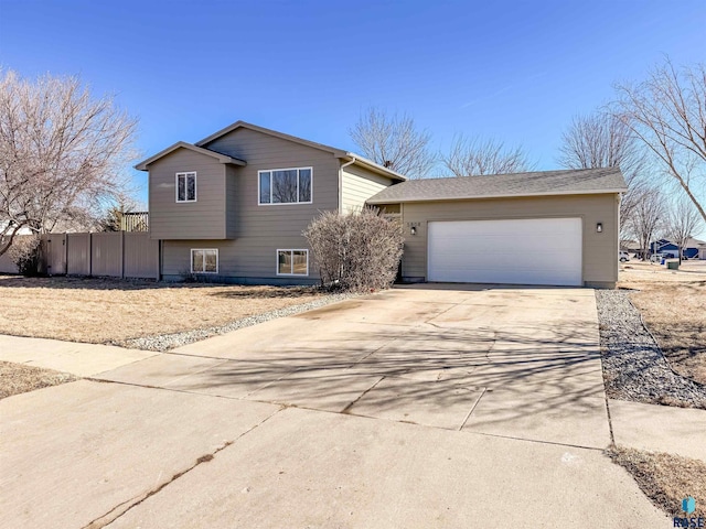 tri-level home featuring concrete driveway and fence