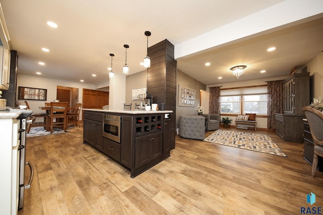 kitchen featuring recessed lighting, light wood-style floors, open floor plan, light countertops, and ornate columns