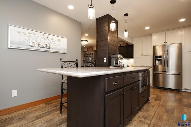 kitchen with stainless steel appliances, a breakfast bar, dark wood-type flooring, and dark brown cabinets