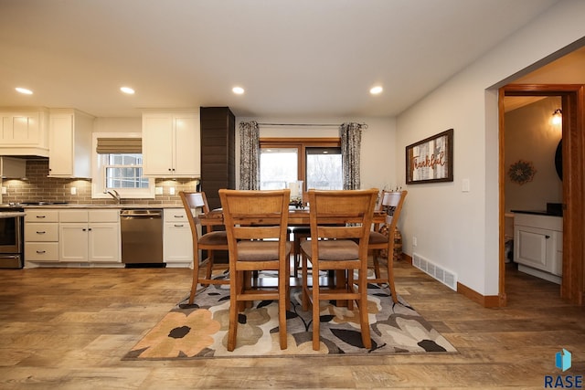 dining space with light wood-style flooring, recessed lighting, visible vents, and baseboards