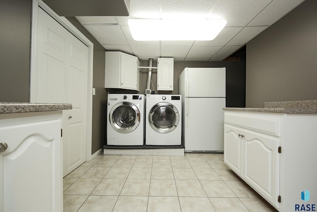 washroom featuring cabinet space, washer and dryer, and light tile patterned flooring