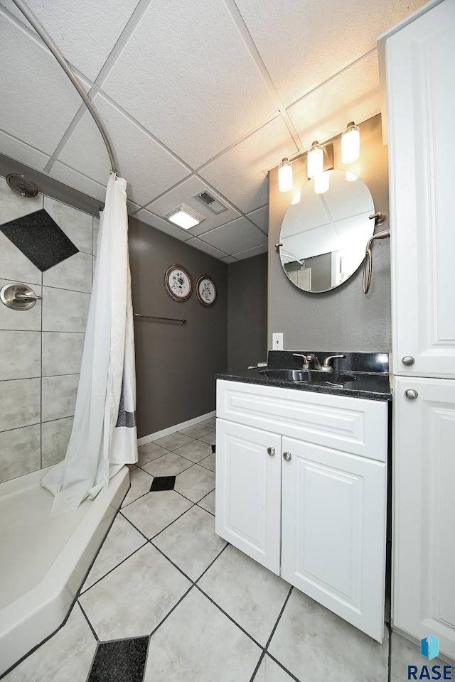 full bathroom featuring a drop ceiling, vanity, visible vents, a tile shower, and tile patterned floors