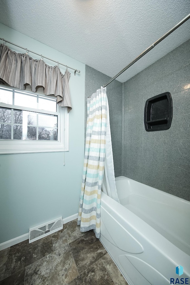 full bathroom featuring visible vents, a textured ceiling, baseboards, and shower / bath combo with shower curtain