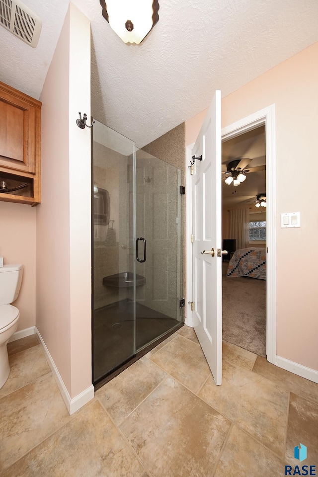 full bathroom featuring visible vents, baseboards, toilet, a textured ceiling, and a shower stall