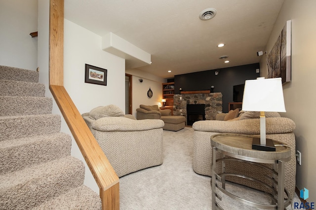 living room featuring carpet, recessed lighting, visible vents, a stone fireplace, and stairs