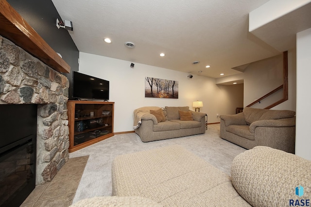 carpeted living area with baseboards, a fireplace, visible vents, and a textured ceiling