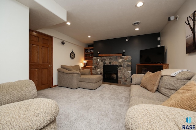 living area with carpet floors, recessed lighting, visible vents, and a stone fireplace