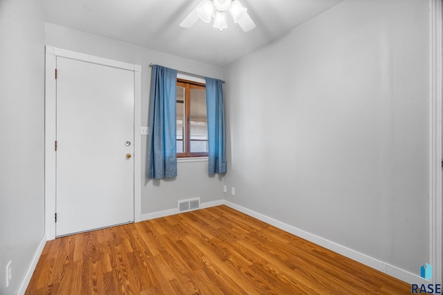 empty room featuring baseboards, visible vents, ceiling fan, and wood finished floors