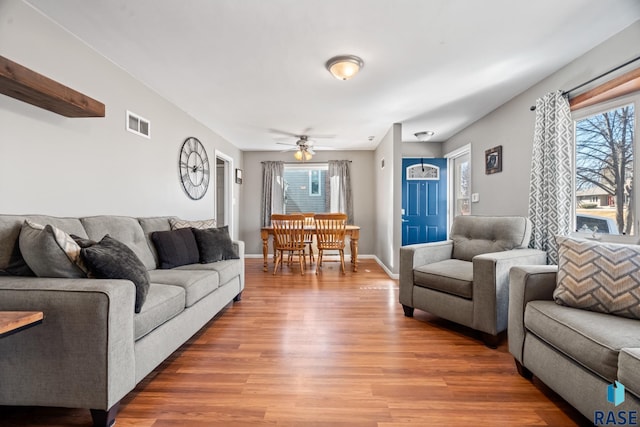 living room with baseboards, visible vents, ceiling fan, and wood finished floors