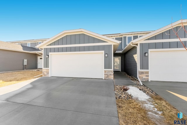 view of front of house with a garage, stone siding, driveway, and board and batten siding