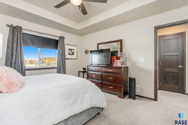 bedroom featuring a ceiling fan, a raised ceiling, light colored carpet, and baseboards