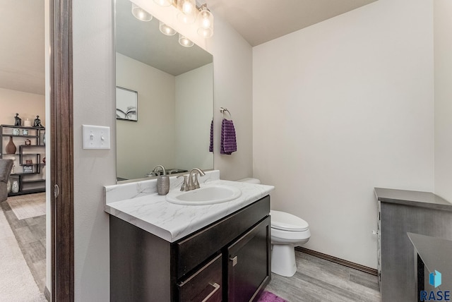 bathroom with vanity, wood finished floors, toilet, and baseboards