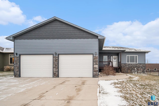 view of front of home featuring driveway, stone siding, and an attached garage