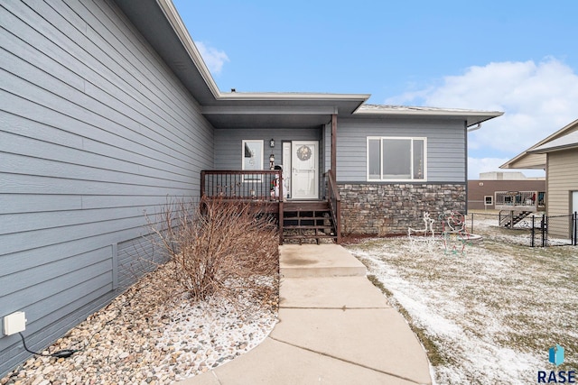 view of exterior entry featuring stone siding, crawl space, and fence