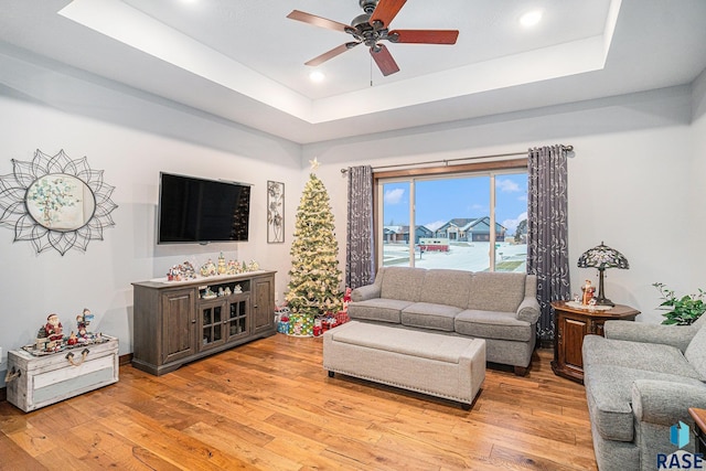 living area featuring recessed lighting, a raised ceiling, light wood-style flooring, and a ceiling fan