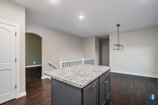 kitchen featuring arched walkways, light countertops, dark wood-type flooring, and a kitchen island