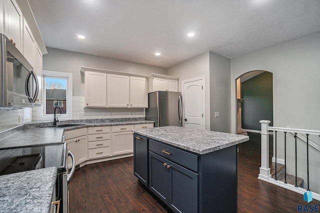 kitchen with electric stove, dark wood-type flooring, freestanding refrigerator, white cabinetry, and a sink