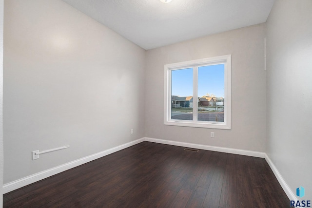 unfurnished room with visible vents, baseboards, and dark wood-type flooring