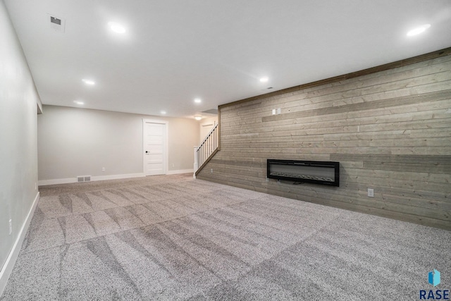 unfurnished living room featuring carpet floors, recessed lighting, visible vents, a glass covered fireplace, and stairs