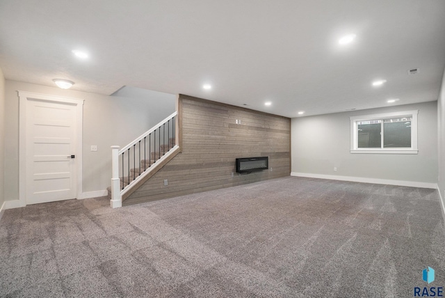 unfurnished living room with recessed lighting, a large fireplace, an accent wall, carpet flooring, and stairway