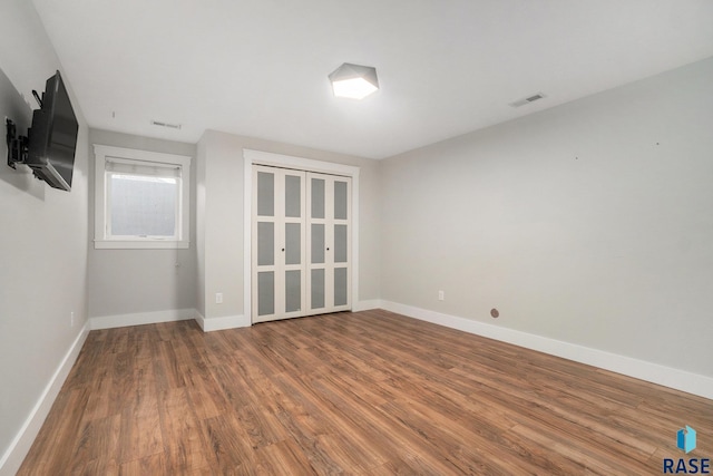 empty room with wood finished floors, visible vents, and baseboards