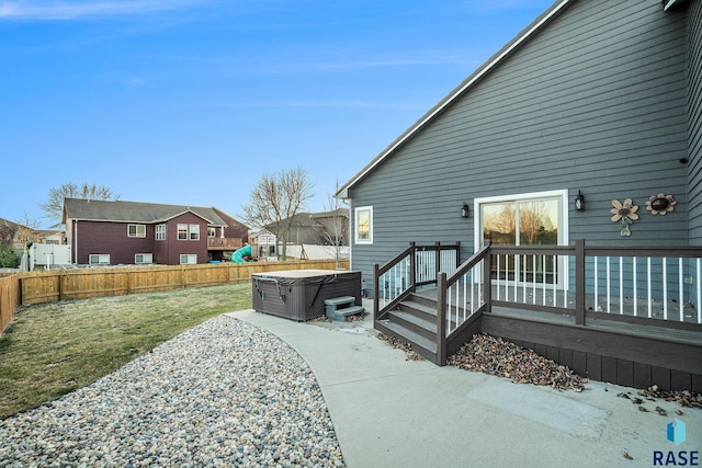 exterior space featuring a hot tub, a patio, a fenced backyard, a residential view, and a wooden deck