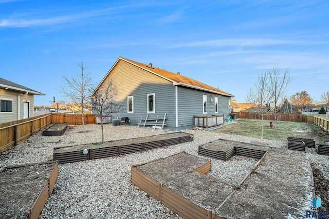 rear view of property with a garden, a lawn, and a fenced backyard