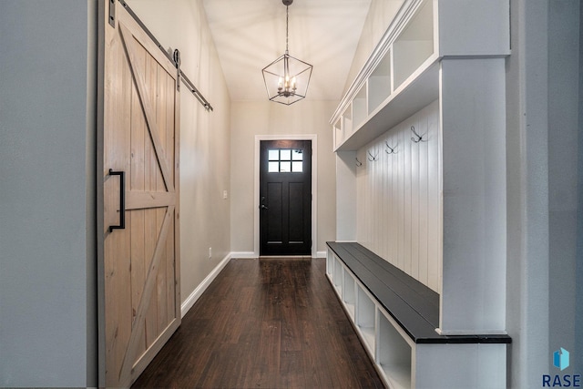 mudroom featuring a barn door, dark wood-style flooring, an inviting chandelier, and baseboards