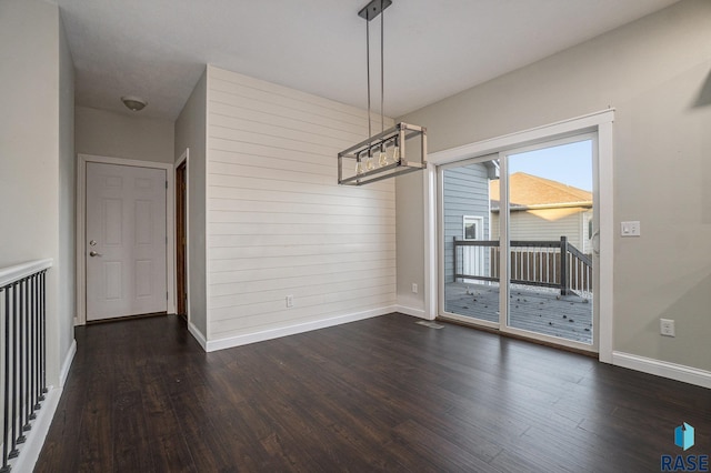 unfurnished dining area featuring dark wood-type flooring and baseboards