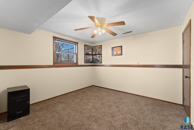 carpeted spare room with a ceiling fan, baseboards, visible vents, and a textured ceiling