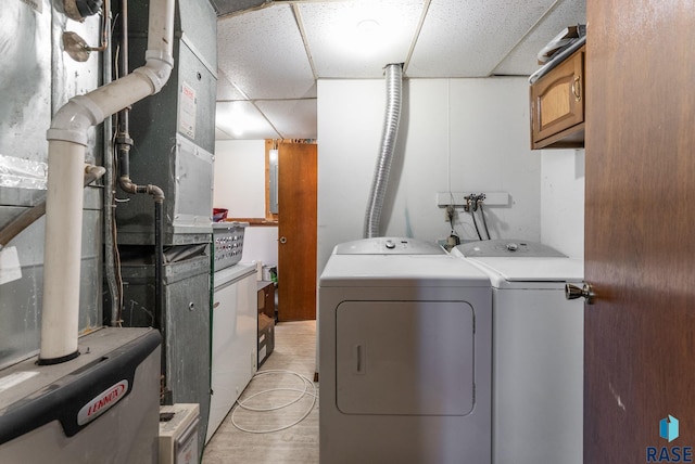 laundry room featuring washer and clothes dryer, cabinet space, and heating unit