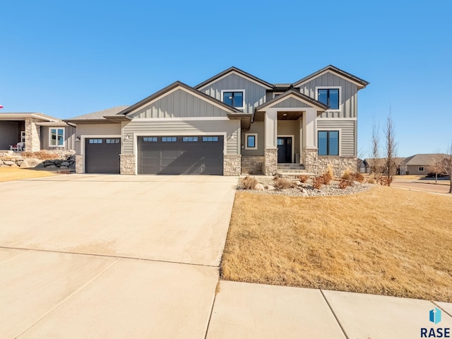 view of front facade with a garage, driveway, board and batten siding, and stone siding