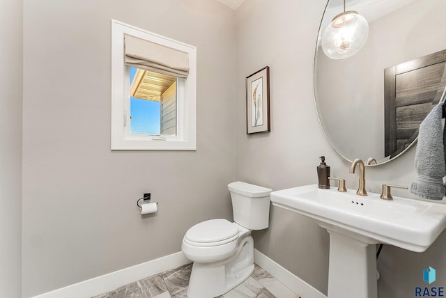 half bath with marble finish floor, toilet, and baseboards