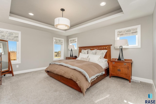 bedroom with recessed lighting, baseboards, a tray ceiling, and light colored carpet